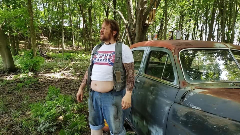 Life in a Box: actor in character by the old car